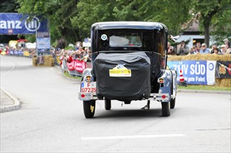 Ford Model A, year of construction 1929, A black vintage car drives on a street at an event,
