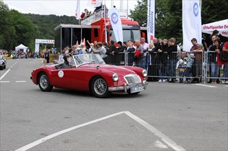 A red convertible vintage car drives on a road at an event, SOLITUDE REVIVAL 2011, Stuttgart,