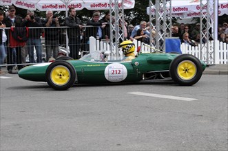 A green and yellow historic racing car with number 212 surrounded by spectators, SOLITUDE REVIVAL