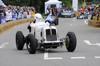 A white vintage racing car at a racing event, surrounded by spectators, SOLITUDE REVIVAL 2011,
