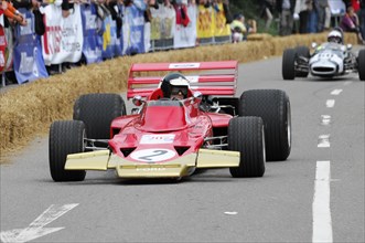 Red formula car in racing action, surrounded by bales of straw and spectators, SOLITUDE REVIVAL