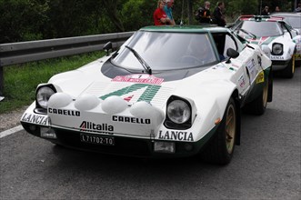 A white Lancia Stratos racing car with green stripes and red accents ready for a rally, SOLITUDE