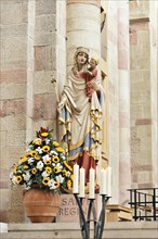 Speyer Cathedral, Colourful sculpture of a saint with child, surrounded by flowers and candles,