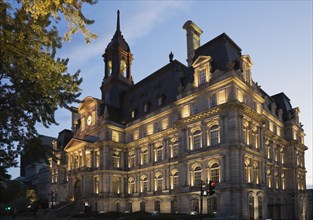 Second empire style multistory Montreal City Hall building facade with lights on at dusk, Old