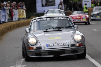A white classic Porsche drives past spectators at a race track, SOLITUDE REVIVAL 2011, Stuttgart,