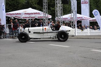 A vintage racing car drives past a crowd of people and advertising banners, SOLITUDE REVIVAL 2011,