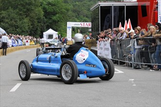 A blue classic racing car with driver in helmet drives past spectators, SOLITUDE REVIVAL 2011,