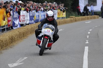 A motorcyclist in racing action on a closed-off track in front of an audience, SOLITUDE REVIVAL