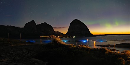Northern lights (aurora borealis) mingle with sunset, sea, striking mountains and fish farm,