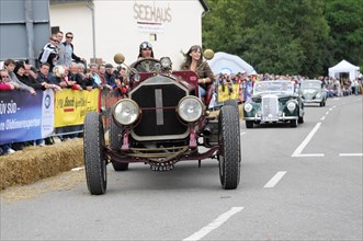 A classic car races in front of spectators on the street, SOLITUDE REVIVAL 2011, Stuttgart,