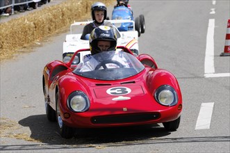 A racing driver in a red sports car during a race with spectators in the background, SOLITUDE