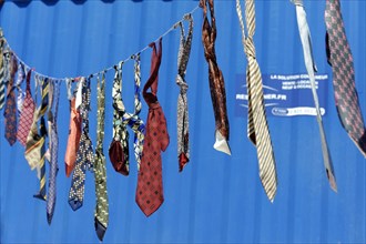 Art bazaar Marseille, Colourful ties hanging on a washing line in front of a blue background,