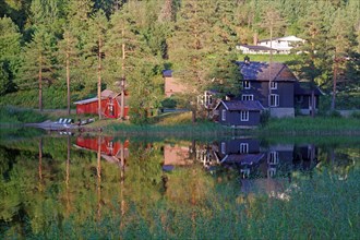 Houses and trees reflected in a quiet lake, Idyll, Morgedal, Telemark, Norway, Europe