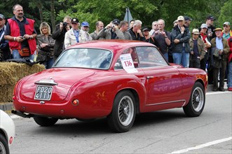 A red vintage sports car drives in front of a crowd at a classic car race, SOLITUDE REVIVAL 2011,