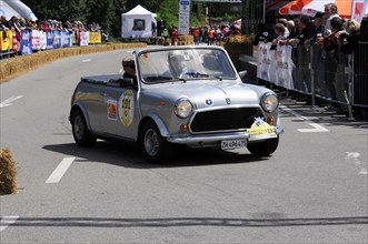 A classic Mini drives on a race track, surrounded by spectators, SOLITUDE REVIVAL 2011, Stuttgart,