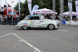 A green vintage car with sponsor logos drives past a crowd at a rally, SOLITUDE REVIVAL 2011,
