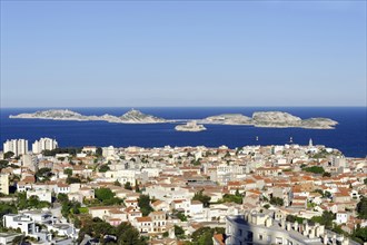 View of a coastal town with blue sea and islands in the background under a clear sky, Marseille,