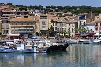Cassis, the harbour, Colourful houses and cafes along a harbour with boats under a clear sky,