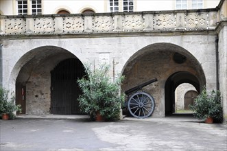 Langenburg Castle, A historic cannon in the courtyard of a castle next to inviting arched gates and