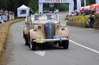 Old beige convertible driving on a road in front of an audience at a classic car race, SOLITUDE