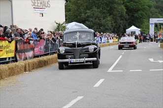 A classic black vintage car drives on a road with a crowd during a rally, SOLITUDE REVIVAL 2011,