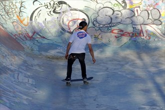 A skateboarder performs tricks in a colourful skate park with graffiti art, Marseille, Departement