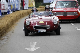 A red vintage convertible takes part in a race, surrounded by spectators, SOLITUDE REVIVAL 2011,