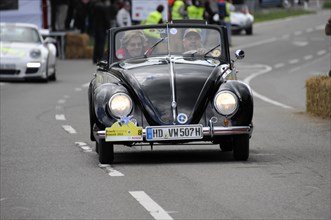 An old Volkswagen Beetle convertible drives past spectators at a car race, SOLITUDE REVIVAL 2011,