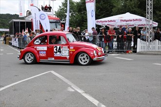 A red Volkswagen Beetle classic car with racing number surrounded by spectators, SOLITUDE REVIVAL