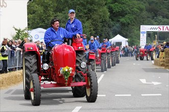 Porsche diesel tractors, Cheerful drivers drive red tractors in a parade in front of an audience,