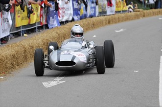 A silver historic racing car curves past bales of straw while spectators look on, SOLITUDE REVIVAL