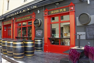 Marseille, Inviting Irish pub with red window frames, barrels as decoration and cafe chairs