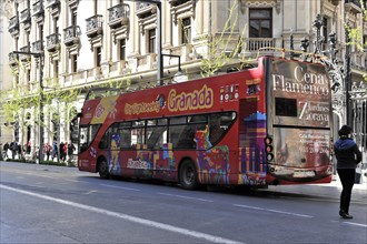 Granada, Colourful sightseeing double-decker bus in a busy city street, Granada, Andalusia, Spain,