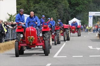 Porsche Diesel Tractors, A row of tractors and their drivers at a parade, surrounded by spectators,