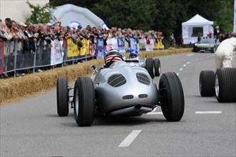 A classic racing car drives past an enthusiastic crowd at a race track, SOLITUDE REVIVAL 2011,