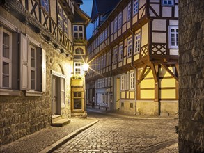 Narrow alley with half-timbered houses and cobblestones in the historic old town in the evening,