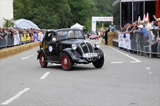 A small black vintage car is cheered by spectators during a street race, SOLITUDE REVIVAL 2011,