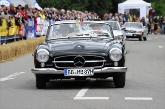 A black Mercedes-Benz convertible classic car drives on a rally surrounded by the public, SOLITUDE