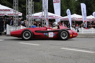Red racing car on a race track with a driver in a racing helmet, SOLITUDE REVIVAL 2011, Stuttgart,