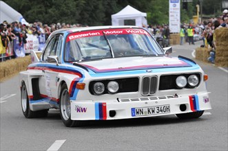 A classic BMW racing car in white, blue and red livery drives past spectators, SOLITUDE REVIVAL