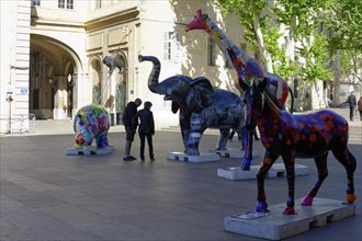 Colourful elephant sculptures on a square with people strolling in the background, Marseille,