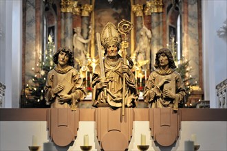 Wuerzburg, Three sculptured figures of saints on an altar with candles and a Christmas tree in the
