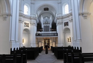 The organ in the Neumuenster collegiate monastery, Wuerzburg, church interior with pews and a large
