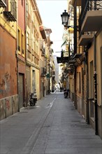 Granada, Narrow city alleyway with buildings and streetlights, no people visible, Granada,