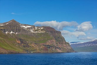 Rugged mountains and steep sea cliffs along the fjord Seyoisfjoerour, Seydisfjoerdur in summer,