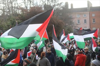 Palestine flags being held high in the air as a protest takes place against Israeli aggression in