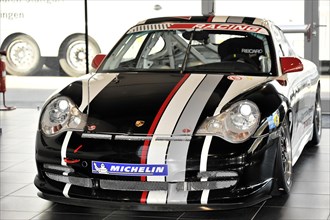 A black Porsche racing car with white and red stripes stands in the showroom, Schwaebisch Gmuend,