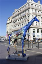 Colourful giraffe sculpture on a busy city street, Marseille, Departement Bouches-du-Rhone,