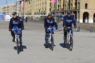 Three police officers on bicycles patrolling a city street, Marseille, Bouches-du-Rhone department,