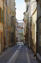 Marseille, Narrow street flanked by traditional buildings and lanterns in daylight, Marseille,